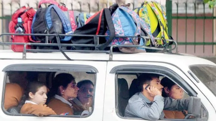 School van driver talking on his phone while driving, backpacks piled on the roof rack