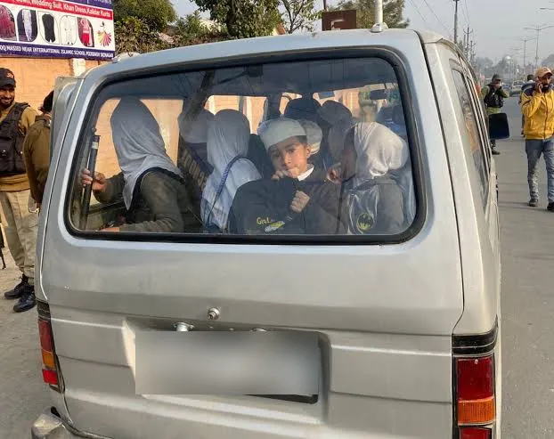 Rear window of a school van completely filled with children pressed against the glass