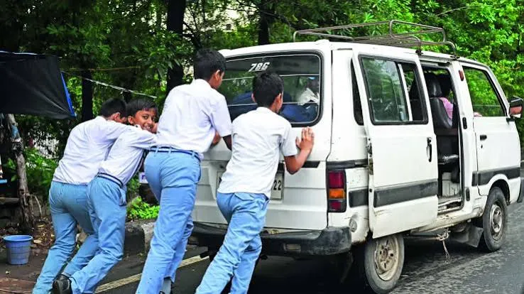Four schoolboys in uniform pushing their school van from behind to get it started